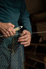 A  man prepares a fishing net for work. Vertical image