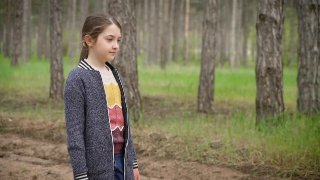 Eight year old girl walking alone through pine forest. Young girl walking alone in pine woods. Child strolling alone through peaceful pine forest