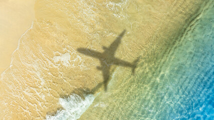 Aerial view of shadow passenger plane silhouette and sandy beach blue sea with waves at sea beach summer vacation sea travel concept	