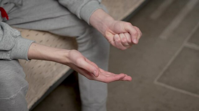 Close up teenage boy hands clenching and unclenching fists. Detailed shot young boy hands making fists and releasing them. Unrecognizable teenager tightening and relaxing fists