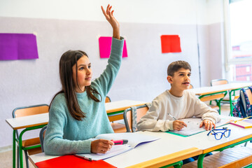 Elementary school student raising hand in classroom to answer question