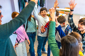 Happy students and teacher raising hands together in classroom