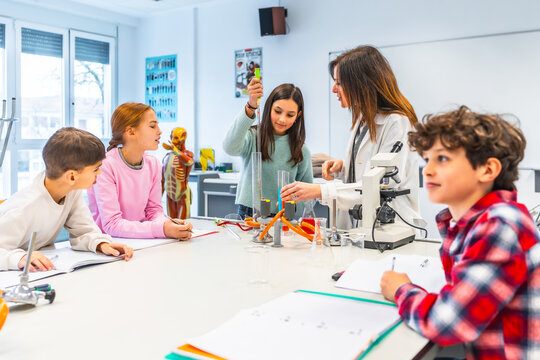 Students performing experiments with teacher in science class