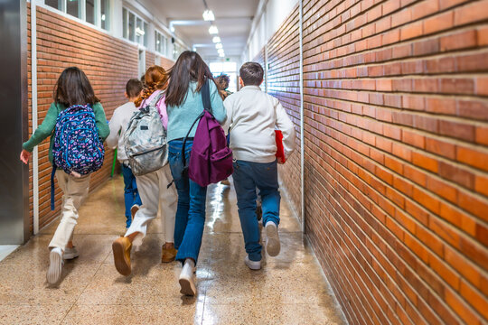 Group of elementary school students running in school hallway