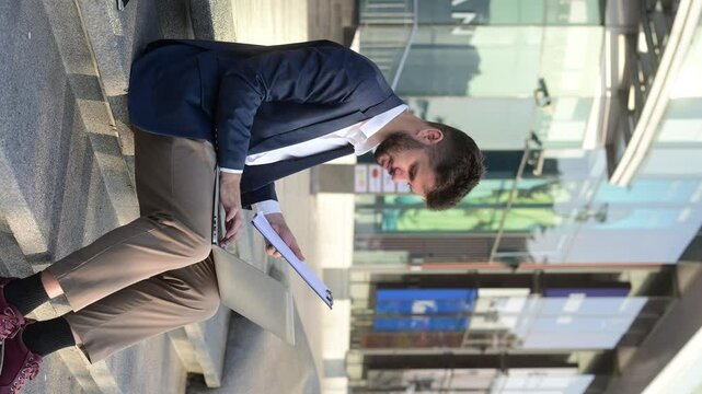 Successful businessman works outdoors near the office holds a tablet