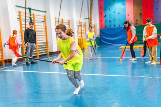 Girl running with hockey stick during gym class at school