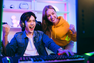 Thrilled gamer celebrates victory with a cheering friend in a neon-lit gaming setup. Perfect for esports, live streaming, competitive gaming, teamwork, digital entertainment, tech innovation content