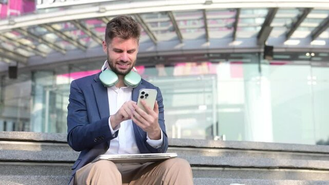 Successful businessman works outdoors near the office holds a tablet