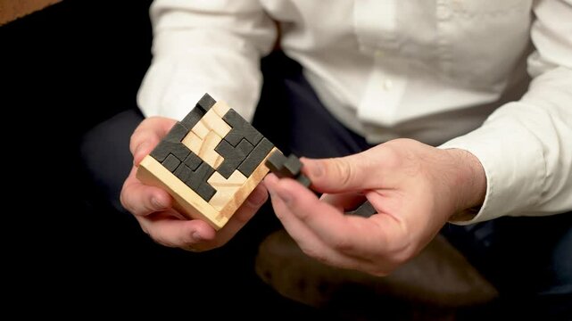 Unrecognizable man assembling puzzle made of blocks to train intellectual abilities. Close up Man putting together block puzzle to enhance mental skills. Unknown male solving block puzzle to improve