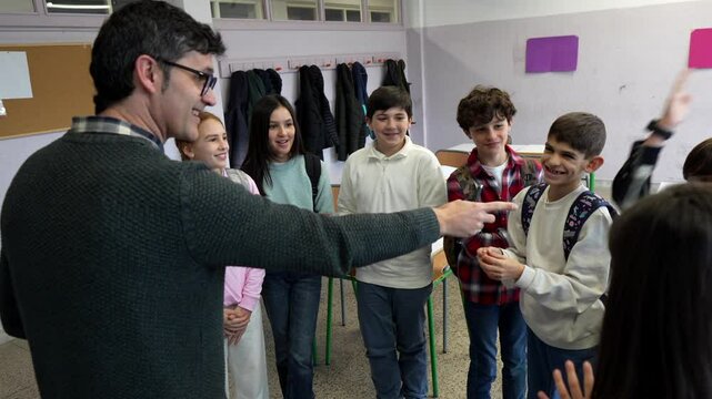 Experienced male teacher guiding elementary school students during collaborative classroom learning activity, encouraging participation and engagement