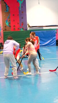 Elementary school students enjoying a dynamic floorball game during gym class, promoting teamwork and physical activity