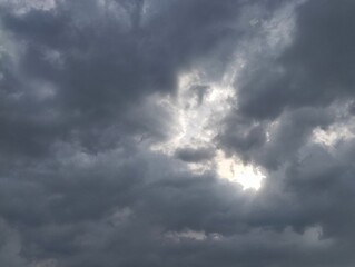 Obraz premium Dramatic dark clouds with sun shining behind, Natural texture background 