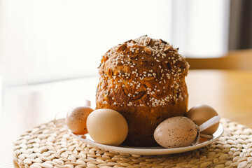 A woman decorates a easter panettone with white icing and colorful chocolate sprinkles while preparing for a spring celebration at home. Fresh flowers add beauty to the setting.