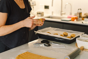 A woman in casual attire prepares dough for baking. She looks pleased and focused, enjoying the baking process in a light-filled kitchen.