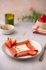 Pink Crepes, blini or thin pancakes with strawberries and whipped cream on a plate on stone table....