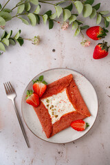 Pink Crepes, blini or thin pancakes with strawberries and whipped cream on a plate on stone table....