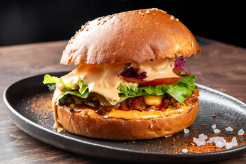 A delicious gourmet burger stacked with fresh lettuce, tomatoes, and purple cabbage, topped with creamy sauce, served on a sesame seed bun. Perfect for food lovers and restaurant menus.