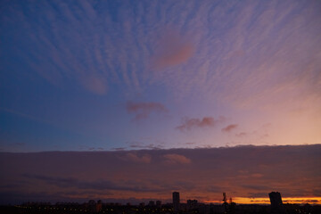 A majestic sunset with purple clouds over the city. Cirrus clouds reflect the last rays of the sun...