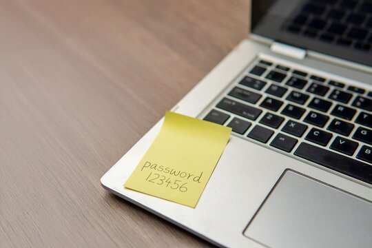 Sticky note with the word "password 123456" on a laptop keyboard. Data protection, password strength concept.