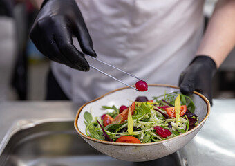 Chef using tongs to add pickled onion