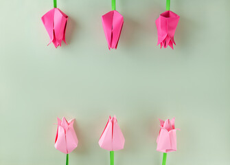 Paper tulips made of colored paper on a green background. Mother's day, women's day concept. Kid's paper craft. Top view, copy space.