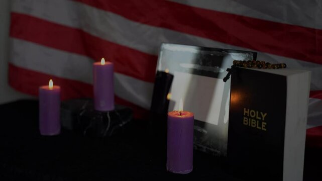     funeral of an American hero, photo frame, candles, a marble urn for ashes, holy bible and spiritual bracelet with black cross