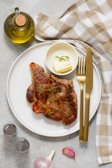 Pork steak with butter and rosemary on a plate. top veiw