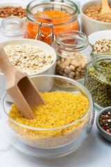 Assortment of cereals and legumes in jars, containers and bowls on a light background. Healthy eating, products, vegetarianism.