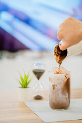 Pouring chocolate into a glass cup with milk