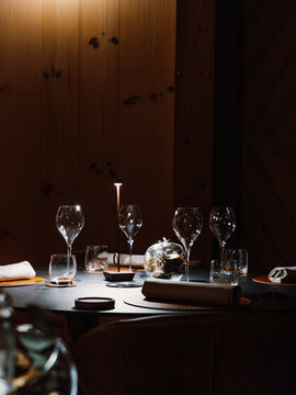 Elegant fine dining setup with wine glasses and candlelight in a cozy wooden interior. A warm and inviting atmosphere perfect for gourmet experiences, romantic dinners, and luxury dining