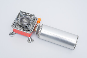 Portable gas stove for camping with a cylinder on a white background. Replaceable gas cylinder and...