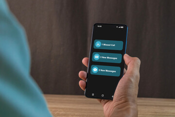 Man holding a smartphone with missed call and new message notification on the phone screen