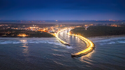 View from a drone at night of the river estuary into the sea in a seaside town