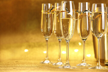 Champagne in glasses on golden background, closeup. Space for text