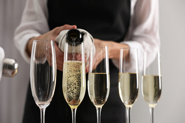 Waiter filling glasses with champagne indoors, closeup