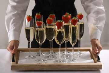 Waiter holding tray with glasses of champagne indoors, closeup