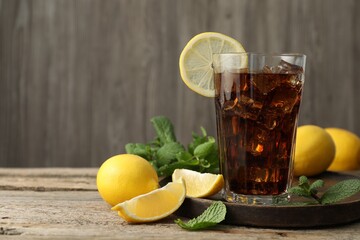 Fresh iced cola with mint and lemons on wooden table, closeup. Space for text