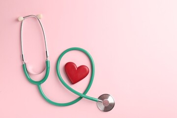 Fototapeta premium Cardiology. Stethoscope and red decorative heart on pale pink background, flat lay. Space for text