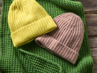 2 Cashmere Strick Wolle Mützen braun gelb auf einem bunt grünen Schal liegend