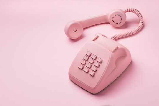 Vintage pink phone on a pink pastel background with the removed telephone handset. High quality photo