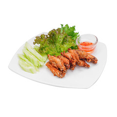 Crispy fried chicken wings sprinkled with sesame seeds, sweet sauce and cucumber salad on a plate, isolated on white background.