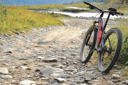 Mountain bike parked on a rocky trail beside a tranquil river during a sunny afternoon
