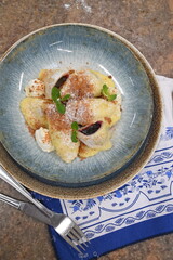 color photo of food traditional Czech food potato dumpllings with fruit, gingerbread, cottage cheese, sugar cream and mint, served on a plate