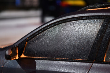Car side window covered in frozen ice and frost after freezing rain in cold weather, winter night...