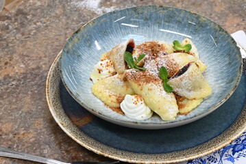 color photo of food traditional Czech food potato dumpllings with fruit, gingerbread, cottage cheese, sugar cream and mint, served on a plate