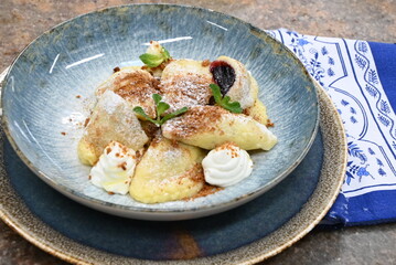 color photo of food traditional Czech food potato dumpllings with fruit, gingerbread, cottage cheese, sugar cream and mint, served on a plate