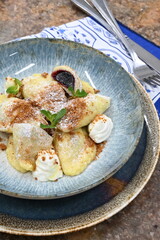 color photo of food traditional Czech food potato dumpllings with fruit, gingerbread, cottage cheese, sugar cream and mint, served on a plate
