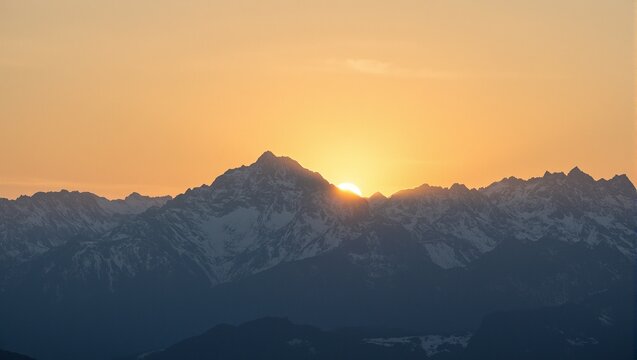 Vivid golden sunrise illuminating snow capped peaks of a majestic mountain range casting long shadows Inspiring and breathtaking scenery