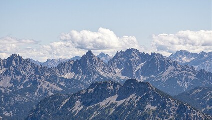 Breathtaking view of remote mountain range with dramatic clouds hovering above jagged peaks Captures untamed beauty of nature