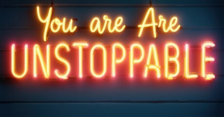 Obraz premium Neon message you are unstoppable flickering in gold, glowing with bright, colorful illumination against a dark background, creating a dynamic and empowering scene